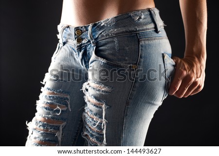 Mid section view of woman wearing jeans in black ang white, dark background.