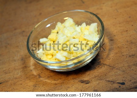 Chopped egg in glass dish on wood background