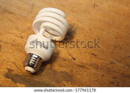 Compact fluorescent light bulb isolated over wood background