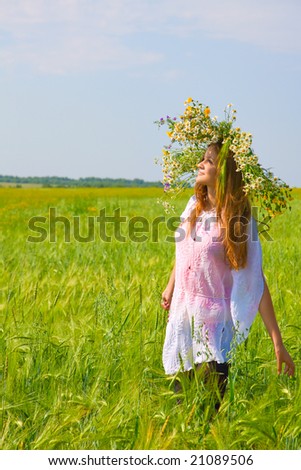 Young girl with chamomile wreath on head stand on meadow