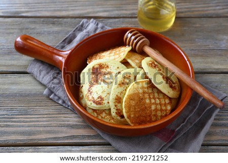Sweet pancakes with honey on a ceramic pan on a wooden boards