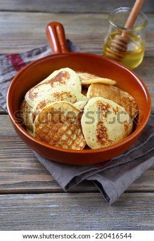 Slim pancakes in a frying pan, food on a wooden background