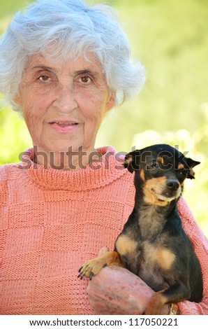 happy old woman with her dog smiling at the camera