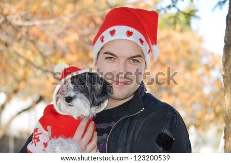 beautiful man  hugging his dog with red christmas hat