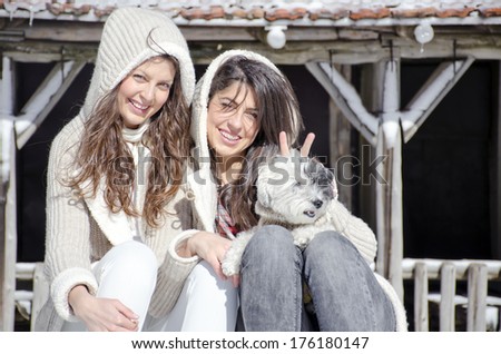 beautiful sisters enjoying the time spent with their little dog in the winter mountain