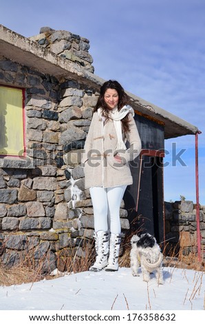 beautiful young woman enjoying the time spent with her dog in the winter mountain
