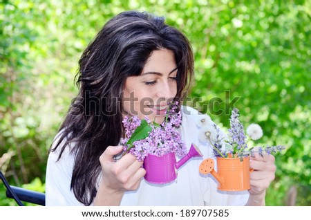 beautiful brunette woman smelling spring flowers in the garden