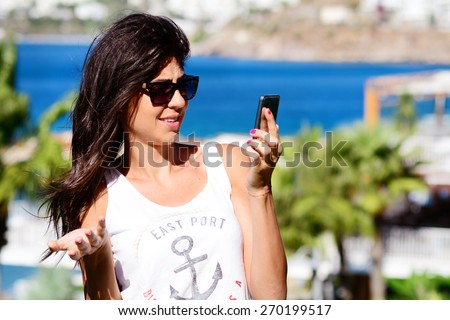 Portrait of beautiful young woman talking on the phone on a sea background