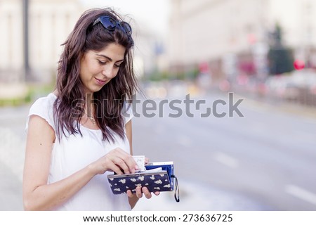 portrait of a beautiful smiling woman with wallet in the hands on the street
