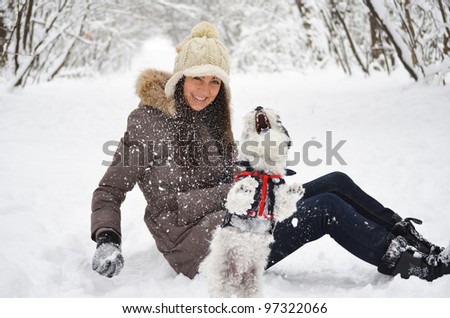 girl playing with her little dog in the winter forest