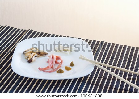 White dish with octopus, mussels and squid on a bamboo table cloth still life