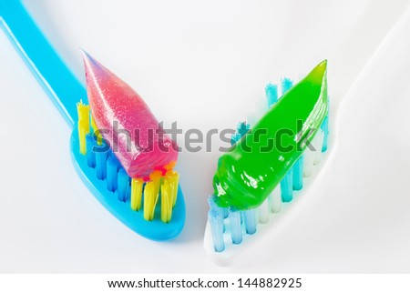 White and blue toothbrushes with gel toothpaste on white background