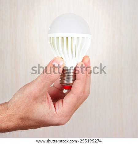 Hand holding a glowing led bulb on a light wood background