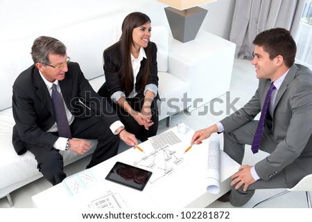 Business people sharing ideas at meeting with documents and tablet on table.