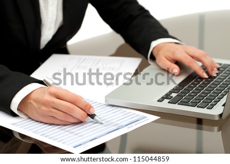 Close up of business woman\'s hands working on laptop and accounting documents.
