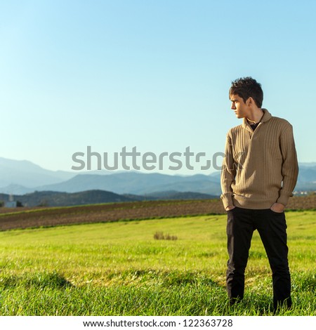 Portrait of young man standing in green field.