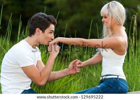 Portrait of young man proposing to girl with kiss on the hand.