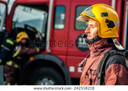 Close up portrait of Fireman staring at danger in front of fire truck.