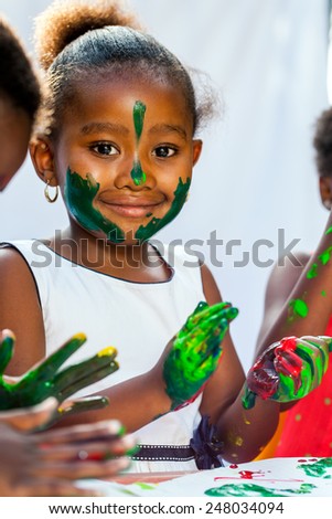 Close up Portrait of African girl painting with friends.Isolated against light background.