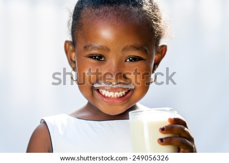 Close up fun portrait of cute African girl showing white milk mustache.Isolated against light background.