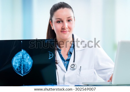 Close up portrait of attractive young female medical student with x ray and laptop at desk.