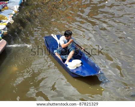 PHATHUMTRANI, THAILAND- OCTOBER 21: Man uses boat as a transportation through water during the worst flooding in decades on October 21, 2011 Rongsit Road, Phathumtrani, Thailand.