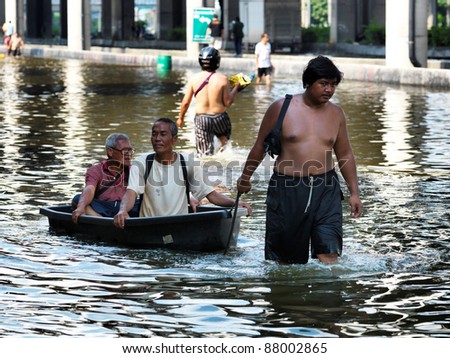 PHATHUMTRANI, THAILAND- OCTOBER 21: Men use boat as a transportation through water during the worst flooding in decades on October 21, 2011 Rongsit Road, Phathumtrani, Thailand.