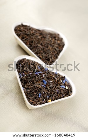 Earl Grey and Lady Grey black loose tea leaves in heart shape, on linen