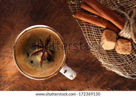 A cup of spiced coffee with anis star and cinamon sticks and sugar