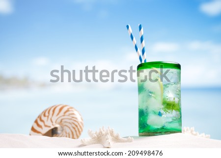 mojito cocktail with ice, rum, lemon and mint   in a  glass  on beach sand and seascape