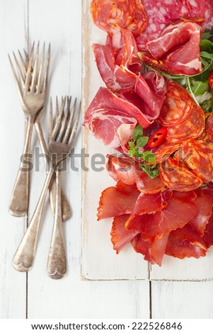 antipasti Platter of Cured Meat,   jamon, sausage, salame  on textured white wooden table