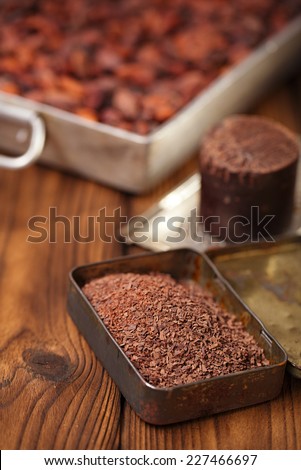 grated dark chocolate in tin with cocoa beans and solid piece in old texured wood