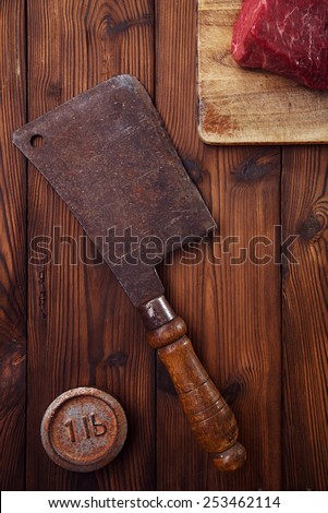meat cleaver butcher knife with raw beef meat fillet  on wooden  table  and 1lb iron weight
