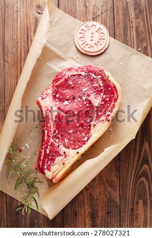 raw beef Rib bone  steak   on paper  and table with home made sign