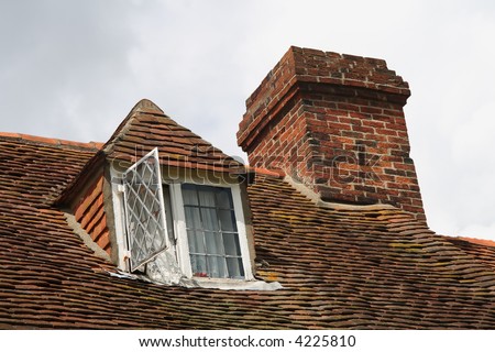 Upper level of old british house showing dormer windows and chimney