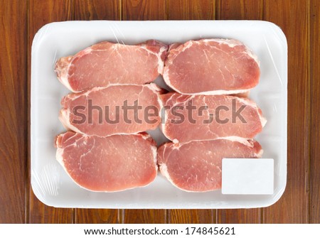 Fresh red meat packed in a poly bag. Isolated over wood