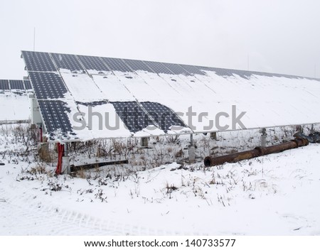 Rows of snow covered solar panels in small solar power plant