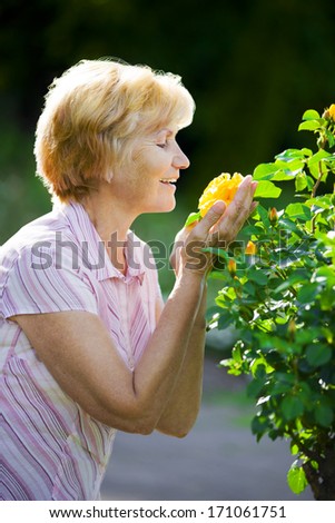 Sentimentality. Mature Old Lady Smelling Yellow Flower