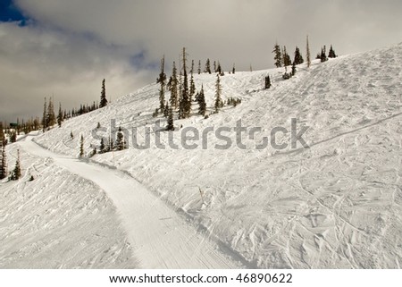 Groomed ski trail between two steep slopes at a resort.