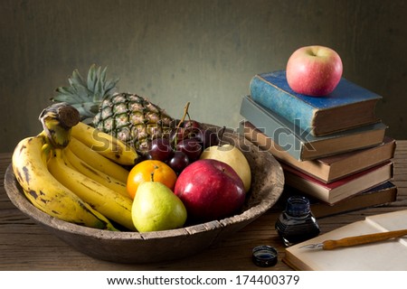 still life, many fruit in old wood tray with stacked old book, inkwell and dip pen