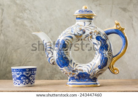 traditional Chinese blue and white ware in teapot and teacup on old wood with cement plaster background
