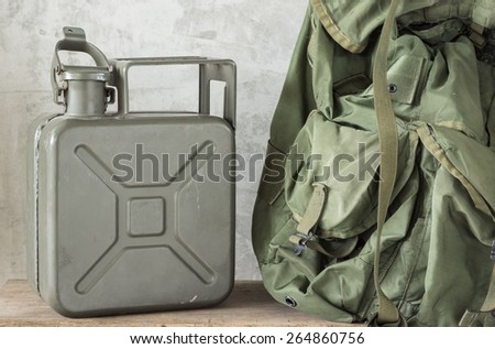 still life photography : Army green jerrycan ( fuel canister ) with part of Military backpack on old wood