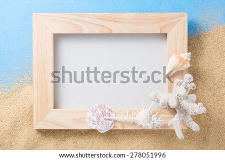 handicraft wood frame with shell and coral on sand and blue texture background