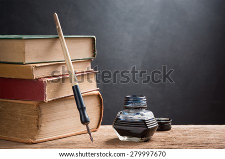 still life photography : inkwell and dip pen with old books on art dark background