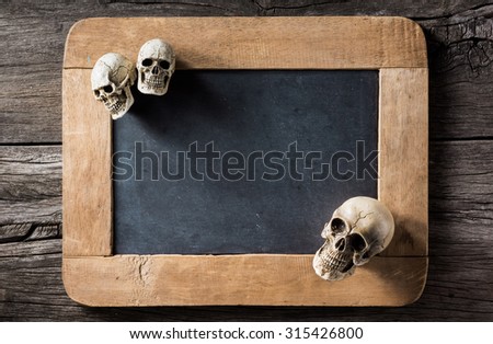 three of skull at the corner of blank slate on old wood