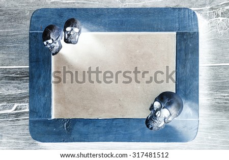 three of skull at the corner of blank slate on old wood in negative film effect