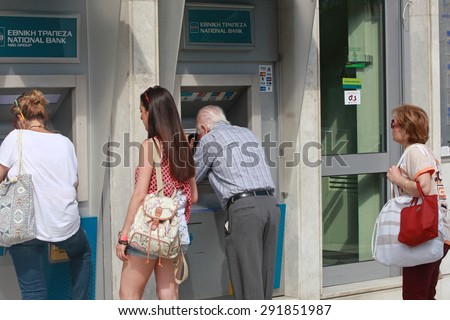 GREECE, Thessaloniki JUNE 29, 2015: Citizens use cash machines outside a closed national bank. Greek banks will stay closed for six days, and capital controls will be imposed when they reopen.