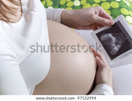 Young pregnant woman expecting a child holding ultrasound