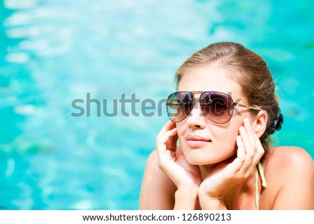 portrait of happy young woman in sunglasses smiling near the pool