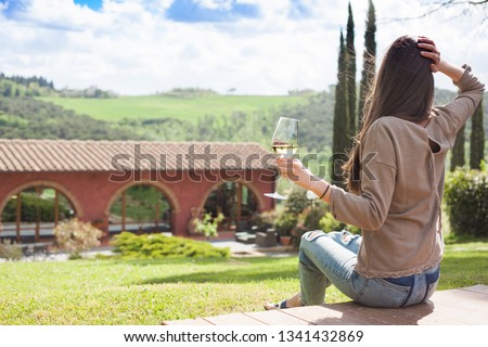 back view of young woman with glass of chilled white wine over Tuscany backgound Foto d'archivio © 
